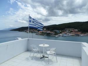 a table and chairs on a balcony with a greek flag at Nicolas Rooms in Fiskardo