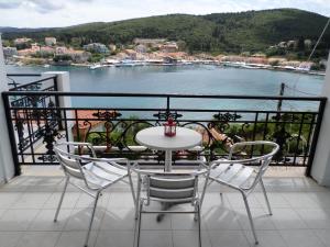 a table and chairs on a balcony with a view of the water at Nicolas Rooms in Fiskardo