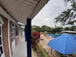 Club Campestre Manantial في Medina: مظلة زرقاء على جانب منزل مع مسبح