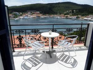 a table and chairs on a balcony with a view of the water at Nicolas Rooms in Fiskardo