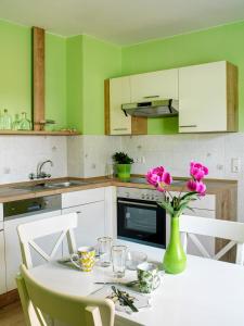 eine Küche mit einem weißen Tisch mit rosa Blumen in einer Vase in der Unterkunft Ferienhaus Wittig in Löbnitz