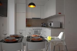 uma cozinha com uma mesa com 2 cadeiras e uma cozinha com armários brancos em Ocean View double Suite em Paço de Arcos