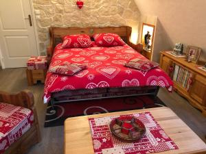 Schlafzimmer mit einem roten Bett und einem Tisch in der Unterkunft Chambre d'hôtes l'Olivianne in Sarlat-la-Canéda