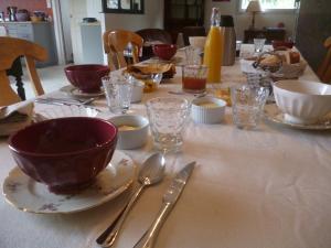 a table with bowls and plates and silverware on it at Chambres d'hôtes de Ty Guen in Trédarzec