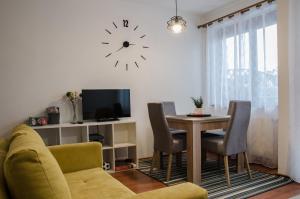 a living room with a table and a clock on the wall at Apartamenty Rohatka in Zakopane