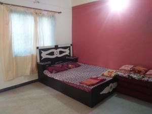 a bedroom with two beds and a red wall at Sai Sneh Holidays Cottage in Alibaug