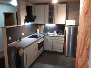 eine Küche mit weißen Schränken und einem Kühlschrank aus Edelstahl in der Unterkunft Ferienwohnung Pliefke in Winringen