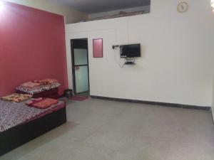 a room with two beds and a tv on a wall at Sai Sneh Holidays Cottage in Alibaug