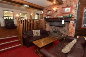 a living room with leather furniture and a fireplace at The Inn On The Green in Ockley