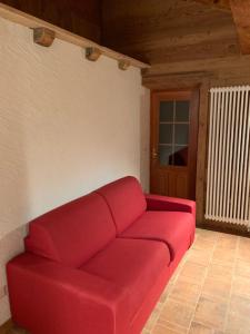un divano rosso in un soggiorno con porta di appartamento Joder a Macugnaga