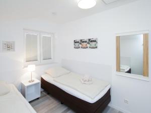 a white room with two beds and a mirror at Haus Emil in Cuxhaven