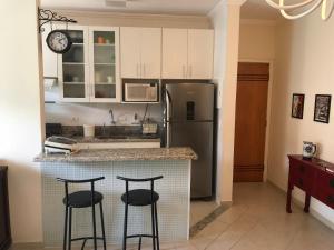 a kitchen with two bar stools and a refrigerator at MARAÚ Premium - espaço, piscina e ar no Itagua in Ubatuba