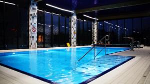 a large swimming pool with blue water in a building at APARTAMENT 5 MÓRZ SPA - NA FALI in Sianozety