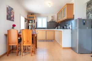 a kitchen with a table and a refrigerator at Casa Sol e Vista in Arco da Calheta
