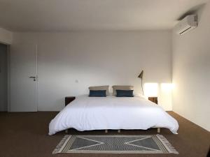 a white bedroom with a white bed with blue pillows at ZN Lodge in Vidago +21 photos