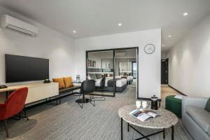 a living room with a couch and a flat screen tv at Quest Notting Hill in Clayton North