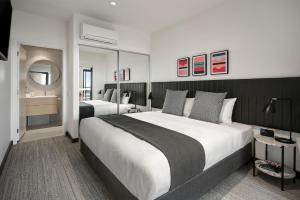 a large bedroom with two beds and a mirror at Quest Notting Hill in Clayton North