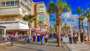 a crowd of people walking down a street with palm trees at Virginia of the sea in Benidorm