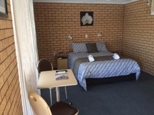 a small room with a bed and a table at cross roads motel in Cobar