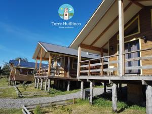 un grupo de edificios de madera en un campo en Cabañas Torre Huillinco, en Huillinco