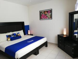 a bedroom with a bed with blue and white sheets at La Estancia Apartments Mazatlan in Mazatlán