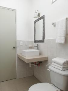 a bathroom with a sink and a toilet and a mirror at La Estancia Apartments Mazatlan in Mazatlán