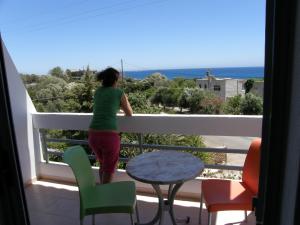 a woman standing on a balcony looking out at the ocean at Megim Hotel in Palaiochora