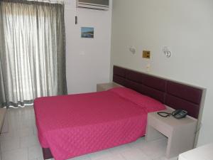 a bedroom with a bed with a pink bedspread at Megim Hotel in Palaiochora