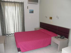 a bedroom with a pink bed and a window at Megim Hotel in Palaiochora