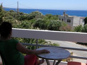 a woman sitting at a table on a balcony at Megim Hotel in Palaiochora