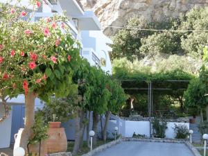 a white building with trees and flowers in a yard at Megim Hotel in Palaiochora