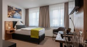 een hotelkamer met een bed en een stoel bij Hotel Drei Tannen in Moosburg