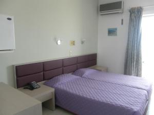 a bedroom with a purple bed and a telephone at Megim Hotel in Palaiochora
