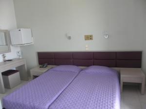 a bed with a purple comforter in a bedroom at Megim Hotel in Palaiochora