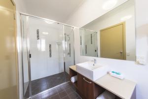 
a bathroom with a shower, sink, and mirror at Rocky Resort Motor Inn in Rockhampton
