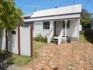 a white house with a white fence and a brick driveway at Pine Cottage in Brisbane