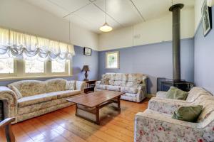 a living room with two couches and a table at Beacon Cottage in Lake Tyers