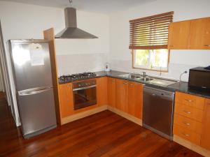 een keuken met houten kasten en een roestvrijstalen koelkast bij Cedar Lookout in Brisbane