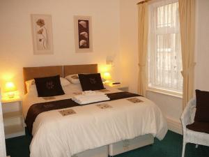 a bedroom with a bed with white sheets and a window at The Craigmore in Blackpool