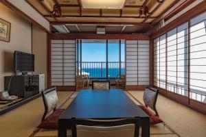 a room with a table and chairs and a view of the ocean at Atami Onsen Sakuraya Ryokan in Atami