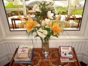 a vase of flowers on a table with two books at The Craigmore in Blackpool