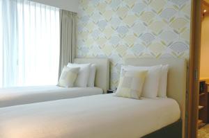 um quarto com duas camas com travesseiros brancos em Shama Island North em Hong Kong