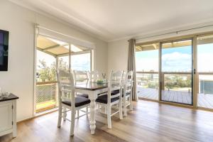 a dining room with a table and chairs and a balcony at Outlook Views in Lake Tyers