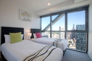 two beds in a room with a large window at Platinum City Serviced Apartments in Melbourne
