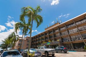 タムニンにあるSureStay Hotel by Best Western Guam Airport Southの建物前駐車場のヤシの木