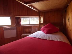 una camera con letto e cuscino rosso di Dune & Domes Pichilemu a Pichilemu