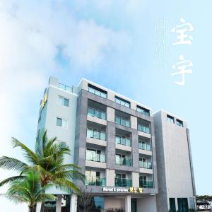 a building with a palm tree in front of it at Bowhill Resort & Pension in Seogwipo