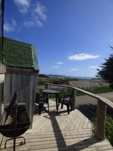 a wooden deck with a table and benches on it at Dune & Domes Pichilemu in Pichilemu