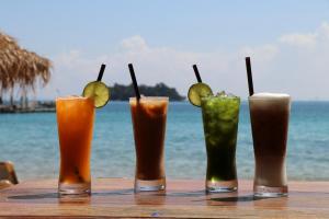 un gruppo di quattro drink su un tavolo vicino all'oceano di Tree House Bungalows a Koh Rong Island