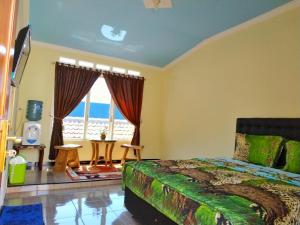 um quarto com uma cama e uma grande janela em Penginapan Kahan em Batu